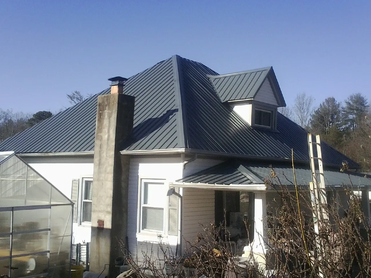 Dark blue standing seam metal roof on a white farmhouse with dormer — Slate & Tile Roof Repair by Roofing Brothers in Paterson