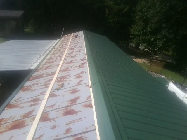 Old rusted panels beside newly installed green metal roofing — Wind Damage Roof Repair by Roofing Brothers in Paterson