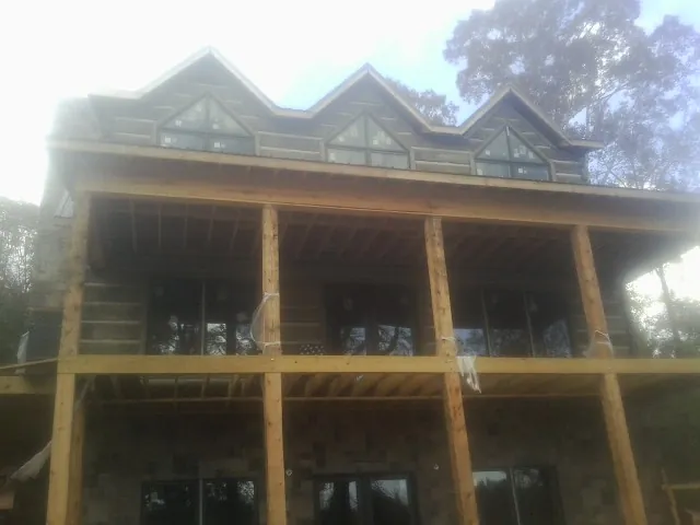 Dormers and porch framing on a large log home under construction — Roof Coating work by our crew in Paterson