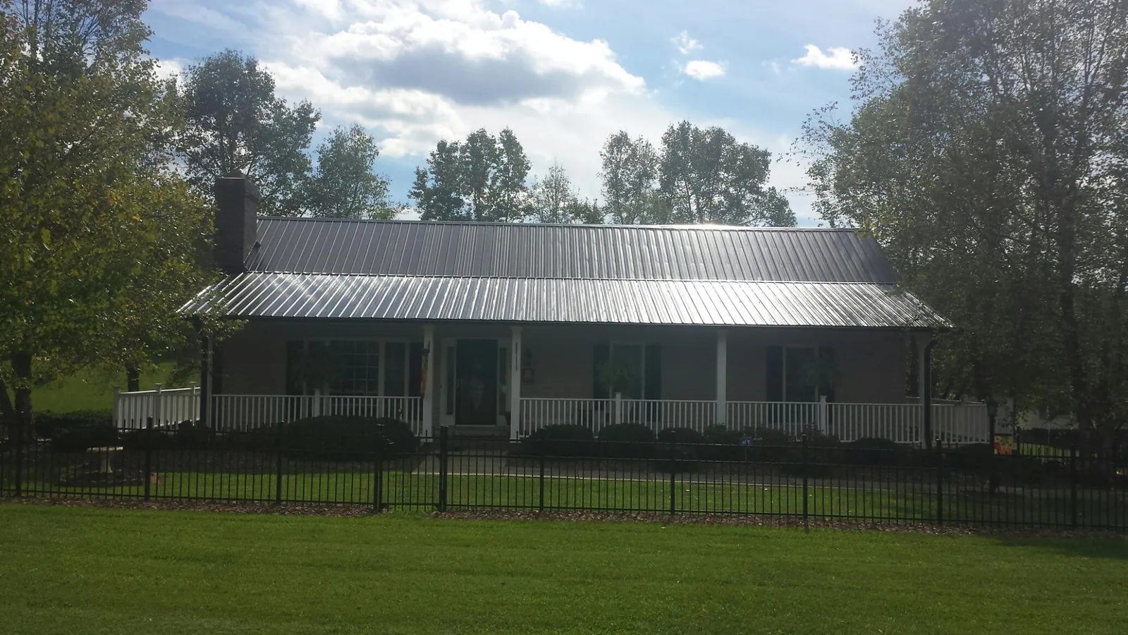 Gray metal roof on a brick ranch with a full width front porch — Gutter Guard Installation work by our crew in Paterson