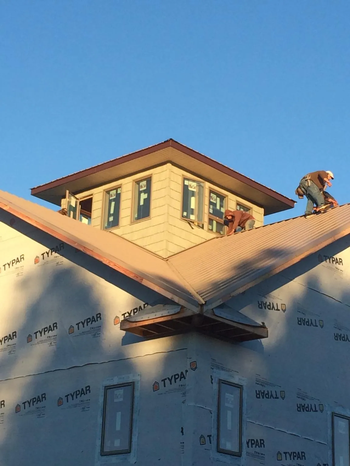 Roofers working around a rooftop cupola on a new metal roof at sunset — Roof Waterproofing in Paterson by Roofing Brothers
